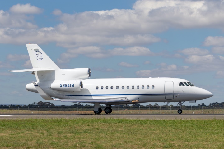 A white with blue stripes Dessault Falcon 900 parked