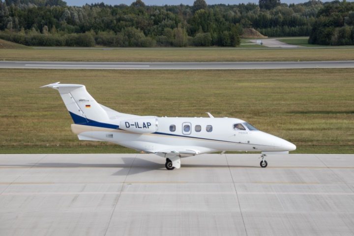 A white Embraer Phenom 100 on the runway